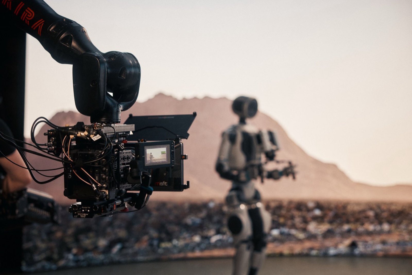 A camera filming a robot against a desert background